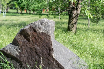 Large granite stone isolated on a grassy area.