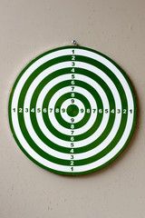 Portrait of dartboard with numbers against concrete wall