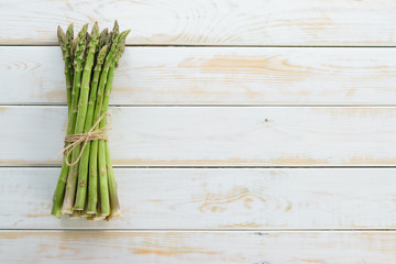Top view of bunch of fresh raw asparagus tied with a burlap twine on a wooden rustic table (copy space)
