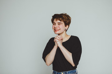 A girl with short hair stands on a white background and smiles