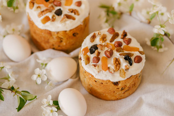 Delicious festive Easter cake, Easter eggs and blossoming twigs of apple tree on linen light background