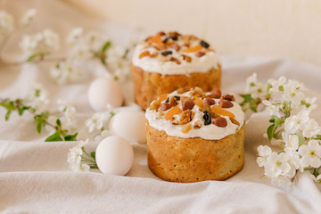  Delicious festive Easter cake, Easter eggs and blossoming twigs of apple tree on linen light background, easter celebration concept
