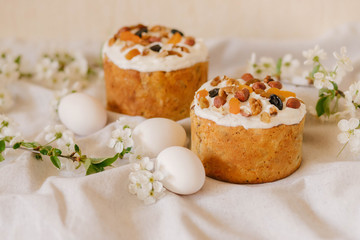  Delicious festive Easter cake, Easter eggs and blossoming twigs of apple tree on linen light background, easter celebration concept