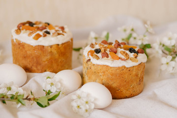  Delicious festive Easter cake, Easter eggs and blossoming twigs of apple tree on linen light background, easter celebration concept