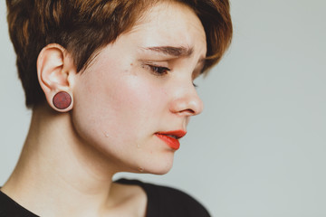 Girl with short hair cries on a white background