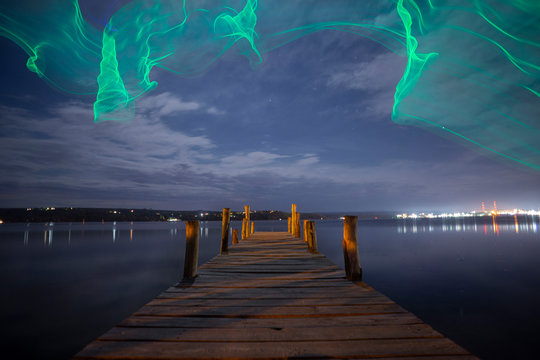 Fishing pier at night with drone imitating northern Aurora Borealis lights