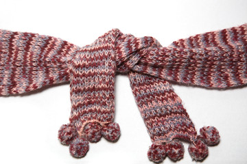 A scarf with round POM-poms made of pink and purple woolen threads of melange color is tied in a knot.
