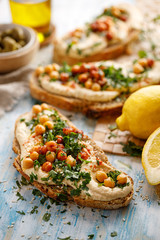 Hummus open faced sandwich with addition chopped fresh parsley, olive oil and chickpeas closeup view. 