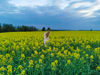 Beautiful blonde girl in a rape field before the storm. Girl and flowers.