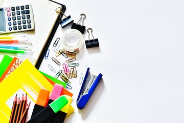 Concept back to school. Top view of colorful school supplies on a white background. Pencils, notebooks, stapler, paper clips, calculator, juicy apple. Place for text.