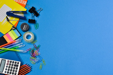 Backpack with school supplies. Concept back to school. Top view of colorful school supplies on a blue background. Place for text