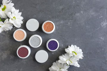 Pattern from natural cosmetics, eyeshadow, flowers on a gray background, copy space, flat lay.