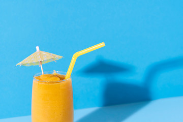 Glass of mango smoothie. Yellow slush with a cocktail umbrella