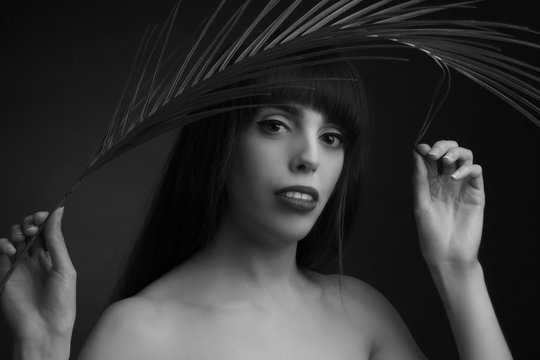 black and white portrait of a young woman with leaf palms.
