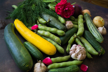 Fresh cucumbers, broccoli, cabbage, cauliflower, onions, garlic, zucchini, beans. A variety of vegetables are on the table.