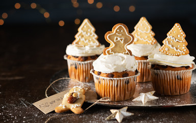Banner Spice cupcakes with cream cheese frosting decorated with a gingerbread cookies. Selective focus, copy space, close up.