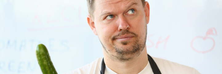 Obraz premium Frustrated Chef Holding Fresh Organic Cucumber