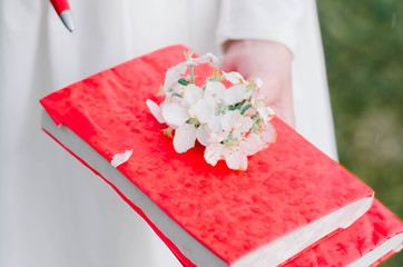 girls holds books of red color in a hand on a book of flowers