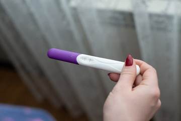 Pregnancy test in female hand on blurred background