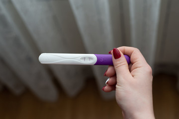 Pregnancy test in female hand on blurred background