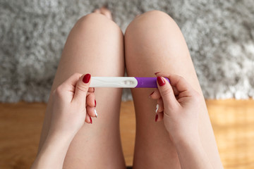 Woman holding a pregnancy test on her knees