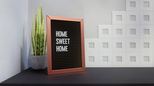 Letter Board with text message: Home Sweet Home. Inside a Modern House, on a Table, Black Flat Surface