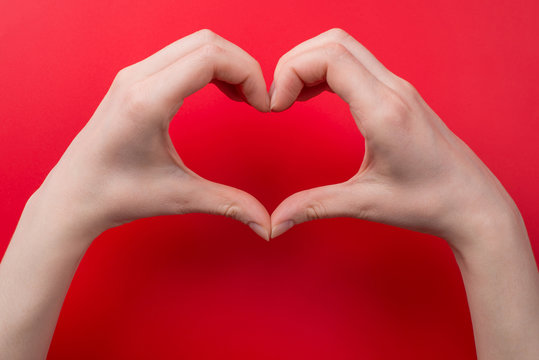 Top pov above overhead close up view photo of woman making heart with her hands isolated on red background