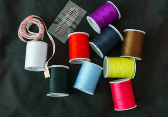 Multi-colored spools of thread close-up on a dark background.