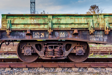 Fototapeta na wymiar Close up fragment of old rusty train cargo wagon. Rusty wheels of an old rail car with weathered peeled green paint. Industrial conceptual scene with trains.
