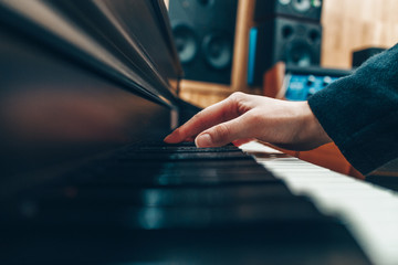 Female hand on the keys of a piano in a recording studio. Record a music track. Create an arrangement. Playing any instrument and piano.