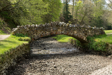 Pebbles and rocks are exposed at a historic stone bridge in Ripon by the dried-up river skell.