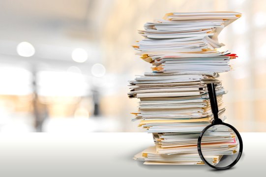 File Folders With Documents And Magnifying Glass On The Desk