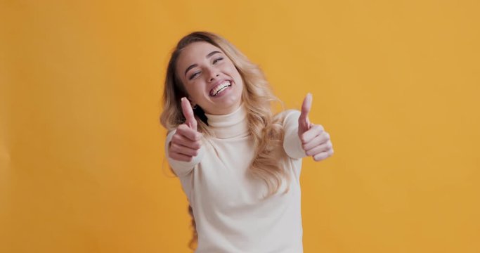 Overjoyed blonde woman showing thumbs up and dancing