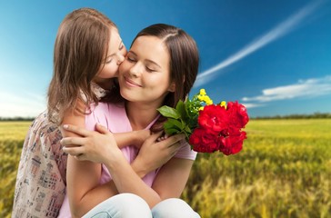 Happy beautiful mother and daughter hugging with a bouquet