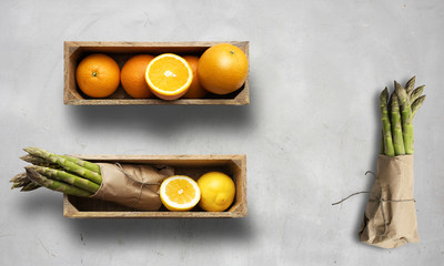 sweet oranges and asparagus' in boxes, on a white chalk background