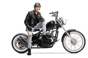 Fototapeta na wymiar Cool young biker with a helmet and a leather jacket sitting on a chopper motorbike