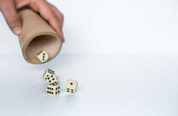 Rolling white dices with brown leather cup