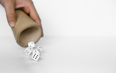 Rolling white dices with brown leather cup