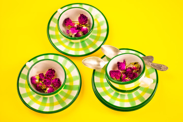 Beautiful little green striped two tea coffee cups and saucers spoons on a yellow background. The concept of home tea drinking, comfort. Banner