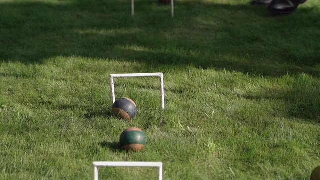 Men in business suits play croquet