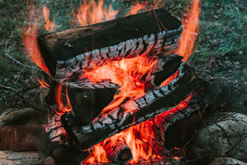 Bright smoldering firewood burned in the fire close-up. Atmospheric warm background with orange...