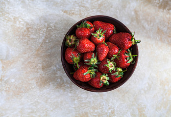 Fresh strawberries in a bowl on a marble background with a discreet scene.