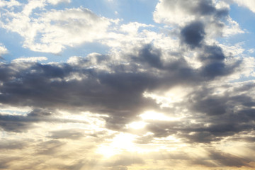 Obraz premium Horizontal photo of a beautiful sunny sky with sun rays shining from behind clouds in blue and yellow colors