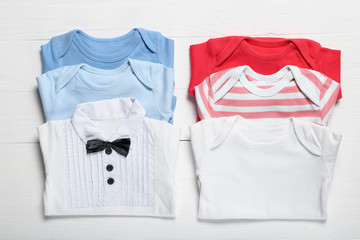 Set of baby bodysuit on a white wooden background