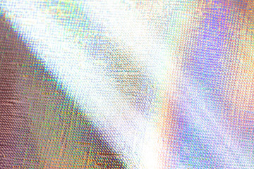 Photo of a real light rainbow crumpled holographic background with a skin texture with rays...