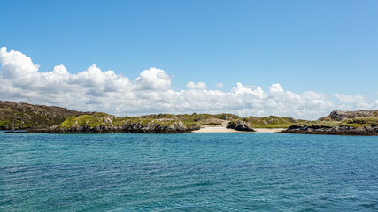 Coastline with rolling hills and small beaches on Inishbofin Island, calm turquoise water, sunny...
