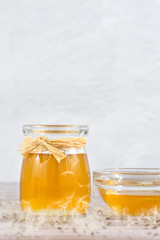 Dandelion jam, honey, jelly in a glass jar on a wooden table, white background with fresh flowers, dandelion airy seed heads, seeds, blow balls. Medicine, healthy food, health benefits from nature