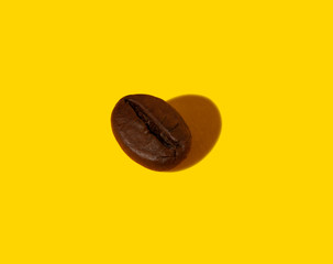 Creative composition of a real closeup macro photography of a coffee bean with a hard shadow in the shape of a heart.