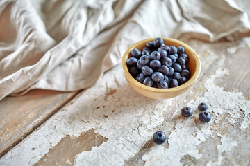 Image of blueberries in wooden bowl on rustic village table.