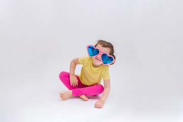 Portrait of a little girl in large glasses heart on a white background with space for text. A cute...